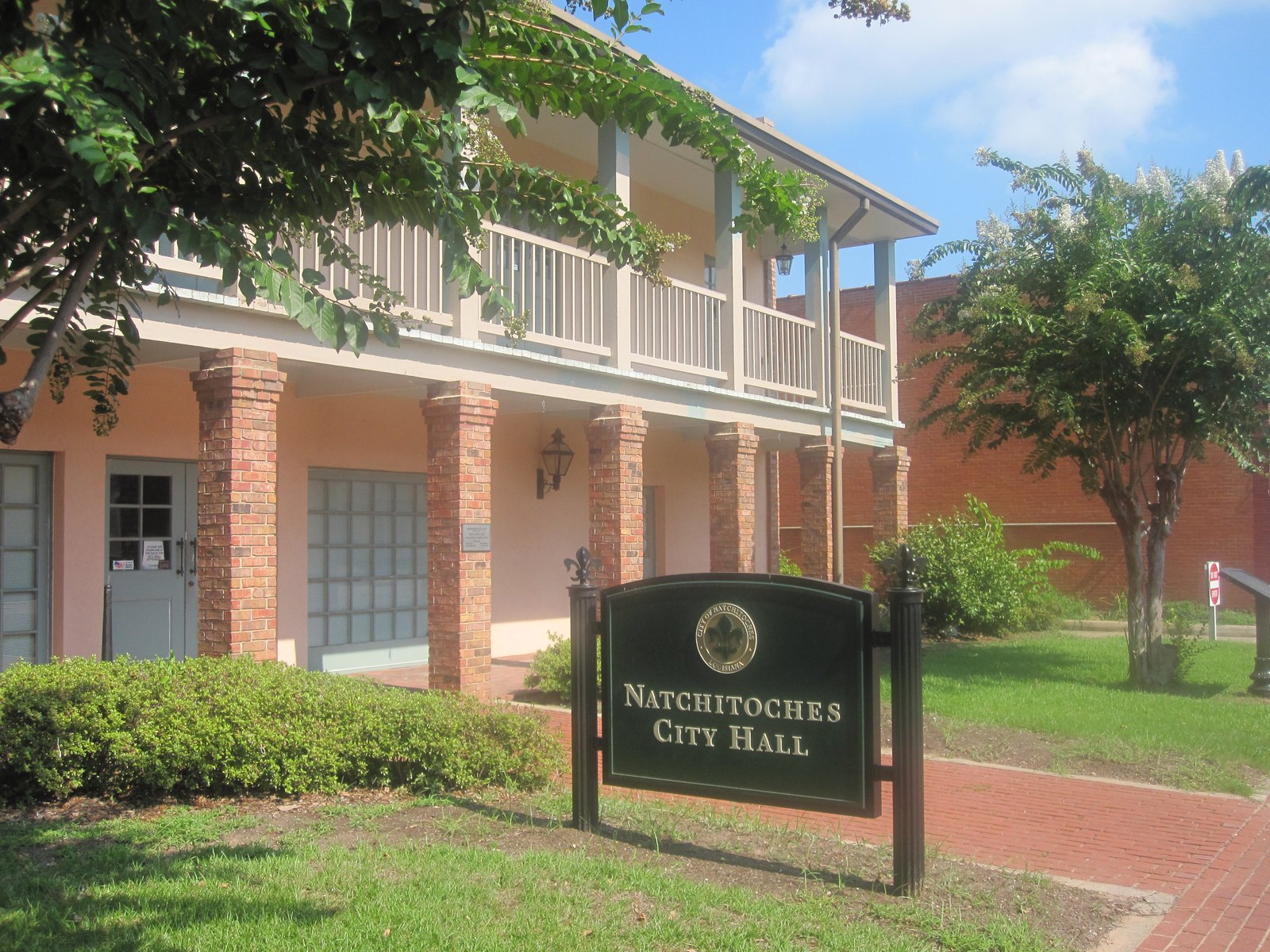 Natchitoches City Hall, with brick columns and an upstairs gallery, behind its sign